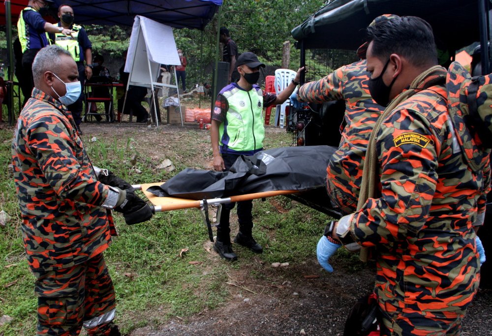 Perak Fire and Rescue Department and police personnel carry body parts believed to be that of two female climbers reported missing in a water surge incident while climbing Gunung Suku, Simpang Pulai, May 16, 2022. u00e2u20acu201d Bernama pic 