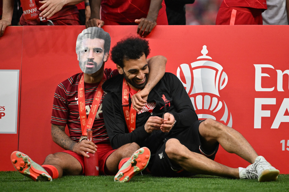 Liverpool midfielder Thiago Alcantara (left) wearing a mask depicting his teammate midfielder Mohamed Salah celebrates with him after winning the English FA Cup final match between Chelsea and Liverpool, at Wembley stadium, in London, May 14, 2022. u00e2u20acu201d AF
