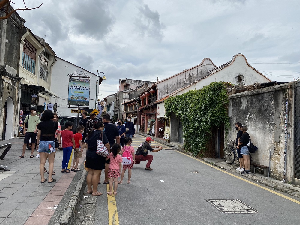 Visitors queuing to pose with the iconic children on a bicycle mural at Armenian Street in George Town. ― Picture by Opalyn Mok