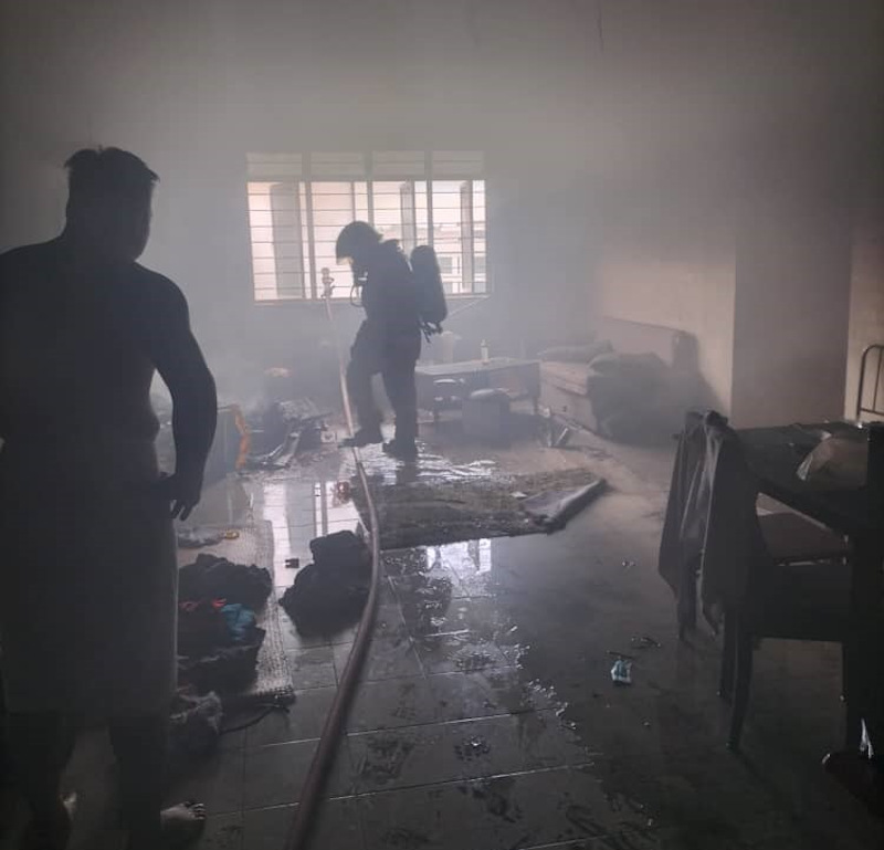 A fireman ensures the fire is completely put out at a police flat at Sungai Merah police station. u00e2u20acu201d Picture courtesy of Fire and Rescue Dept