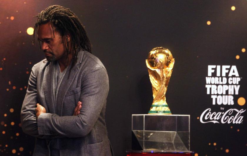 Former French international soccer player Christian Karembeu stands next to the World Cup trophy during the World Cup Trophy Tour in Algiers November 22, 2013. u00e2u20acu201d Reuters pic