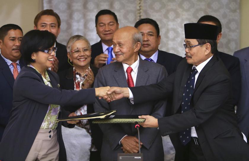 Government of the Philippines (GPH) chief negotiator Miriam Coronel Ferer shake hands with Moro Islamic Liberation Front (MILF) chief negotiator Mohagher Iqbal (right) as they exchange peace agreements between both parties at the GPH-MILF Formal Explorato