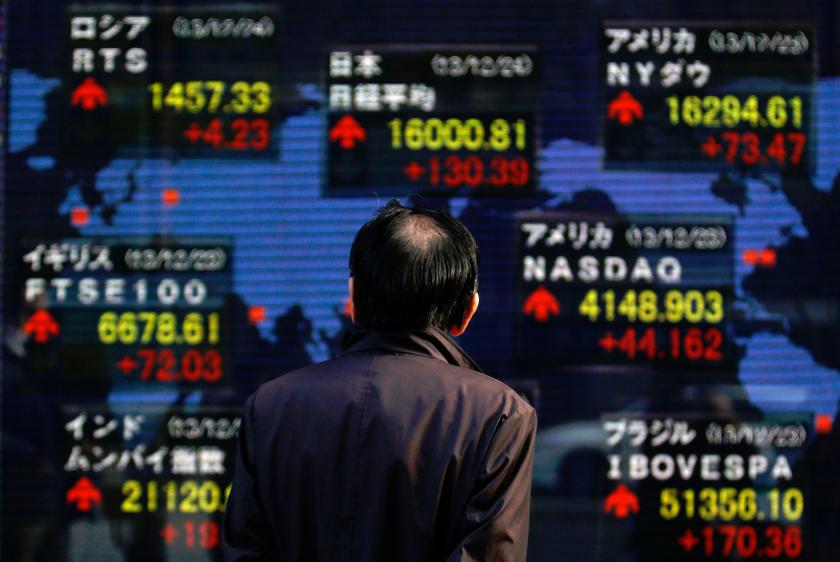 A pedestrian looks at an electronic board displaying various countries' stock market indices outside a brokerage in Tokyo December 24, 2013. u00e2u20acu201d  Reuters pic