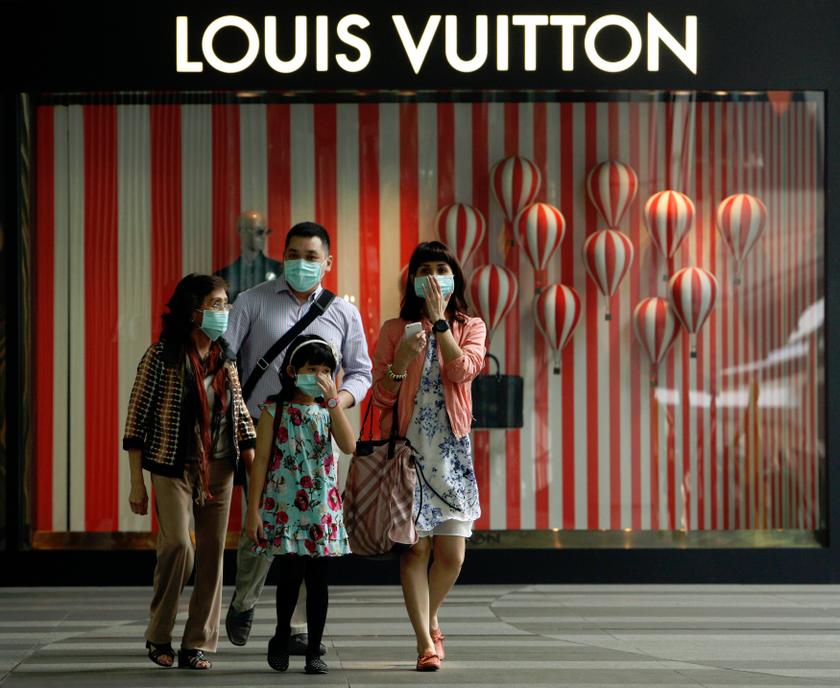 A family wearing masks walk past a Louis Vuitton shop display in Singapore's Orchard Road shopping district June 21, 2013. u00e2u20acu201d Reuters pic