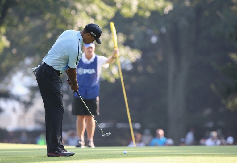 Tiger Woods of the United States hits a putt on the tenth green as his caddie Joe LaCava tends the flagstick during the first round of the 95th PGA Championship on August 8, 2013 in Rochester, New York. u00e2u20acu201d AFP pic