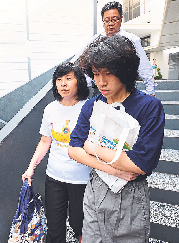 Singapore teenage blogger Amos Yee (R), accompanied by his mother Mary Toh Ai Buay (L) and father Alphonsus Yee (behind), walking out from the state court in Singapore on July 6, 2015. — Picture from AFP
