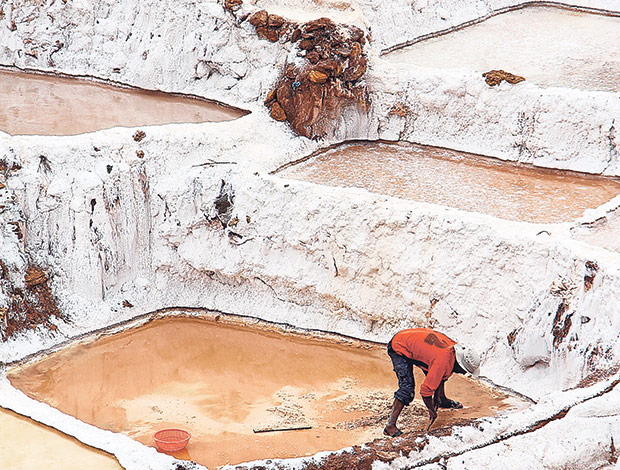 A salt farmer working in his family's salt pond, which is passed down through the generations.