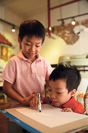 Loving older brother Jaden helping Branden with his drawing.