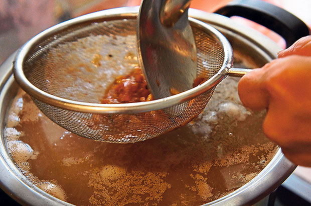 Add tamarind juice to the broth, using a sieve to separate the juice from the tamarind.