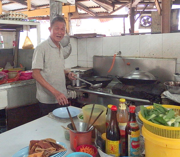 The patriach of the stall beneath the big tree is still busy at the kitchen.