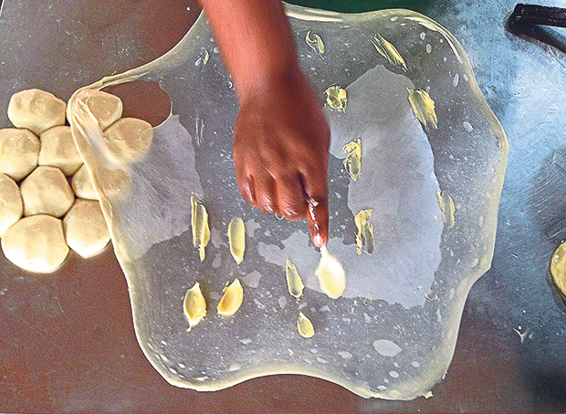 At Pasar Air Panas, Arif dots the dough with Planta for his popular roti of the same name