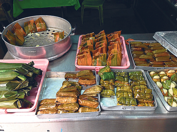 A selection of steamed kuih, all wrapped in banana leaves in various styles, at the cooked section of Pasar Chow Kit