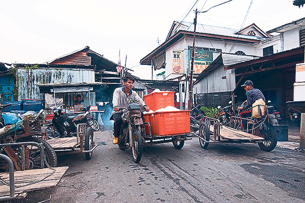 Workers at Sungai Udang jetty transporting containers filled with ice and fishes to be frozen and sent to markets and traders
