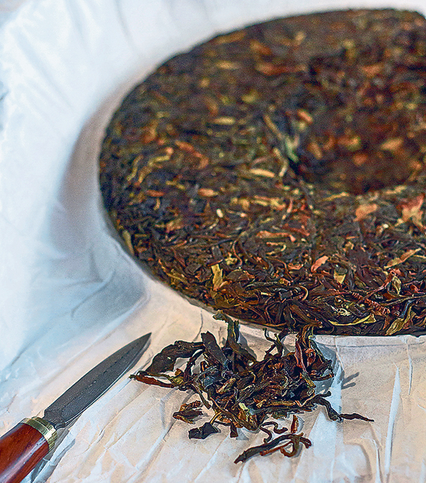 A special knife is used to pry flakes of tea from the cake of pu’er