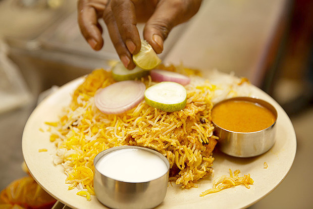 Adding a piece of cut lime to the biryani served at A P Bhavan.