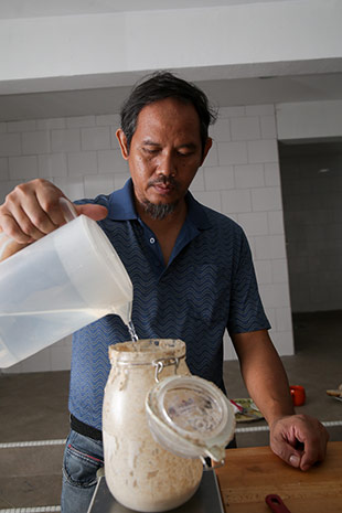 Dinie ‘feeding’ a jar of sourdough by adding flour and water.