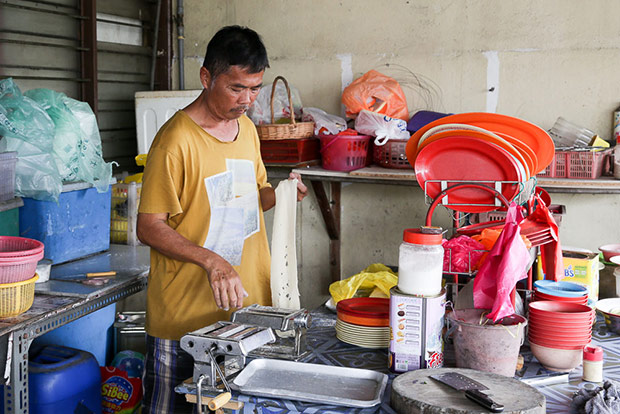 Before frying, he makes the noodles from dough that is flattened.