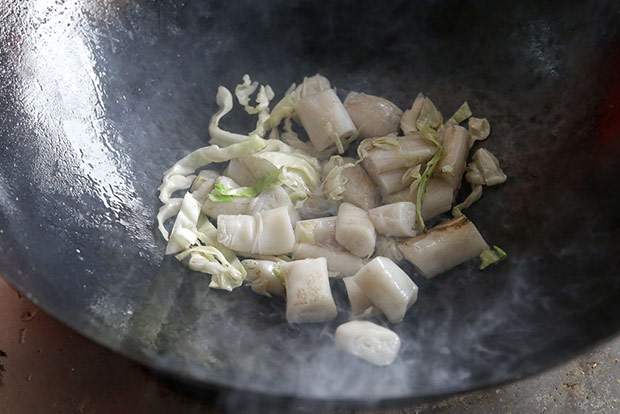 Cut up pieces of the rolled chee cheong fun is pre-fried in the wok with sliced cabbage.