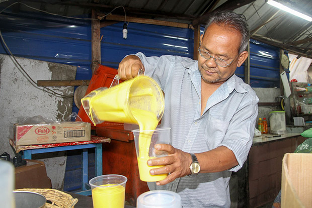 Tok Abah pours out the mangga susu into the 1 litre cup.