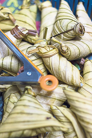 Lepat kacang, glutinous rice and  black-eyed beans wrapped in triangular packets using daun palas (fan palm leaves).