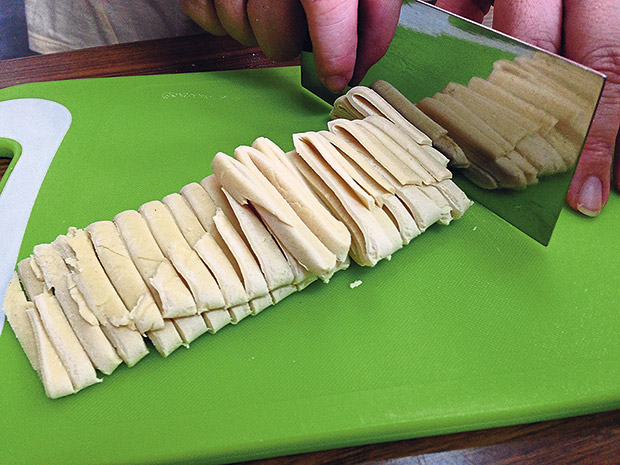 After resting the dough, the noodles are sliced precisely and evenly.