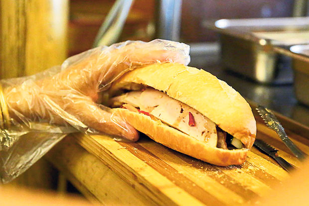 Upon your order for Bánh mì, they will prepare the bread and stuff it with roast pork, chả lụa, pickles and fresh coriander leaves.