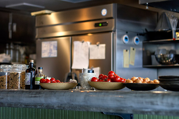 Dishes of ripe tomatoes and small yellow onions on the counter top.