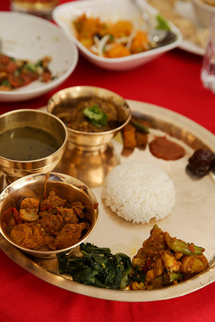 The Thakali set (from bottom clockwise): Aloo Simi, Sabji, Pork Messing, Dal, Kukhura Ko Masu, Mula Ko Achar, chutney, Lapsi and rice in the middle.