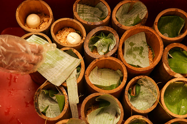 The bamboo tubes filled with biryani is covered with banana leaf to prevent moisture from dripping inside.