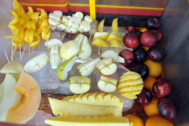 Fresh cut fruits that customers can enjoy immediately are kept cool with blocks of ice underneath.