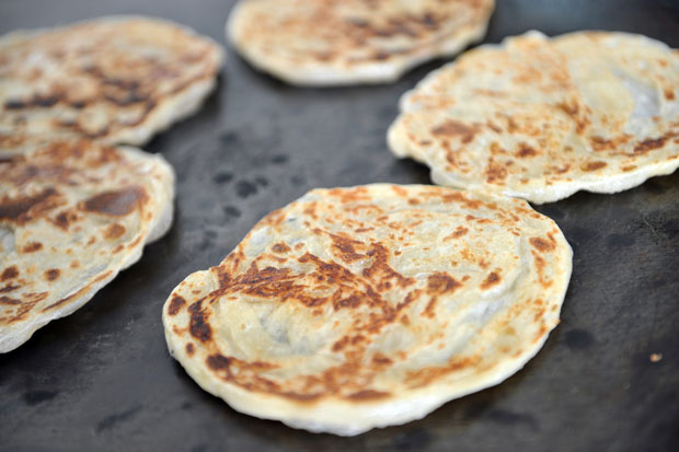Frying up a pan of roti canai.