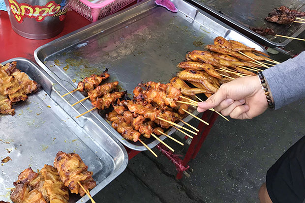 Selecting pieces of gai yang (grilled chicken).