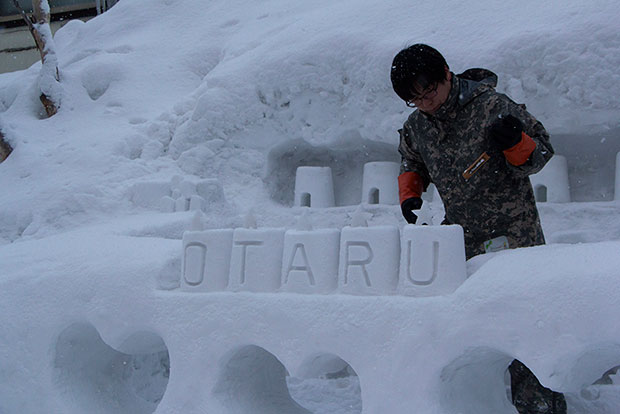 An artist carving out the name of the town in snow