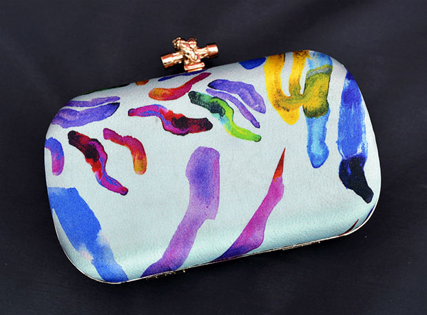 Wear this beautiful Biru minaudière decked in painted fabric from artist, Dura Hana Korumtallee.