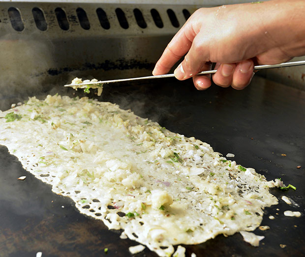 Chopped onions are slowly added for the onion dosa.