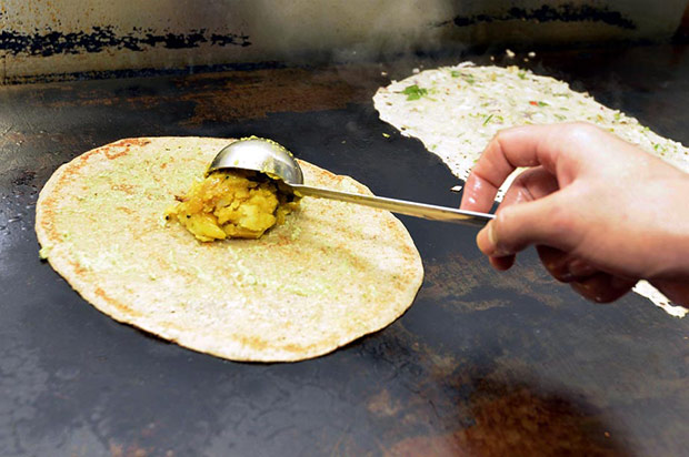 A spiced potato filling is added on top of the half cooked dosa.