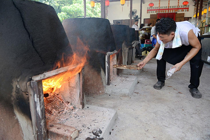 Kegy Chong checking the wood fire of the ceramic kilns placed in front of the restaurant