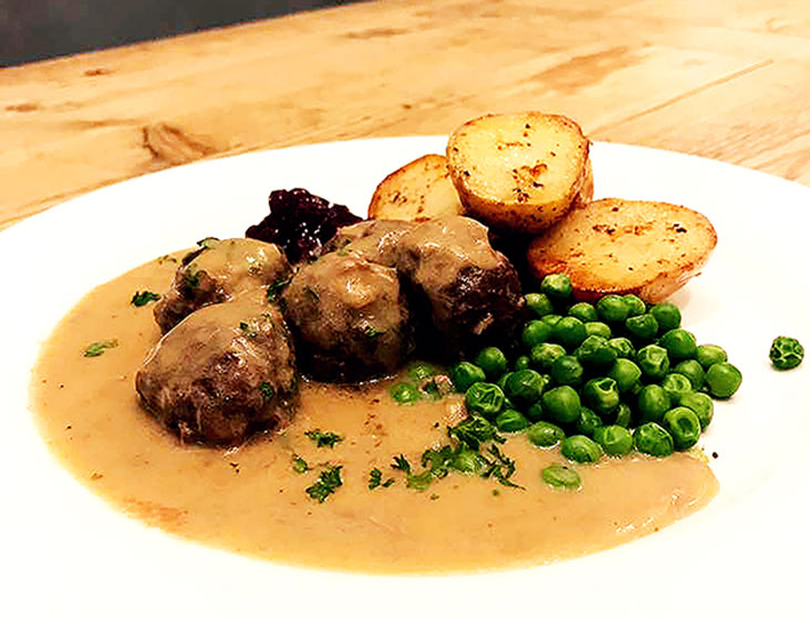 Kjøttkaker med brun saus or meatballs served with roast potatoes, peas, brown sauce and lingonberry preserve