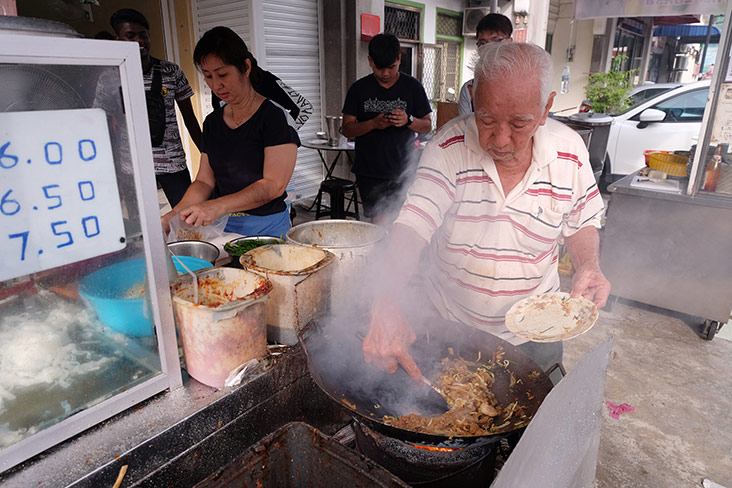 Tan Chooi Hong frying up char koay teow at his stall in front of the coffee shop he and his son just opened along Siam Road.