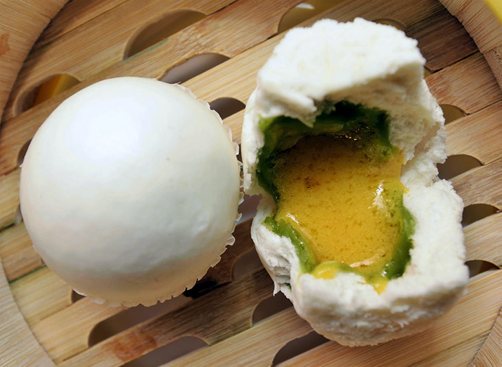 The double taste custard bun combines savoury, sweet salted egg yolk custard with pandan lotus paste, all encased in a fluffy bun.