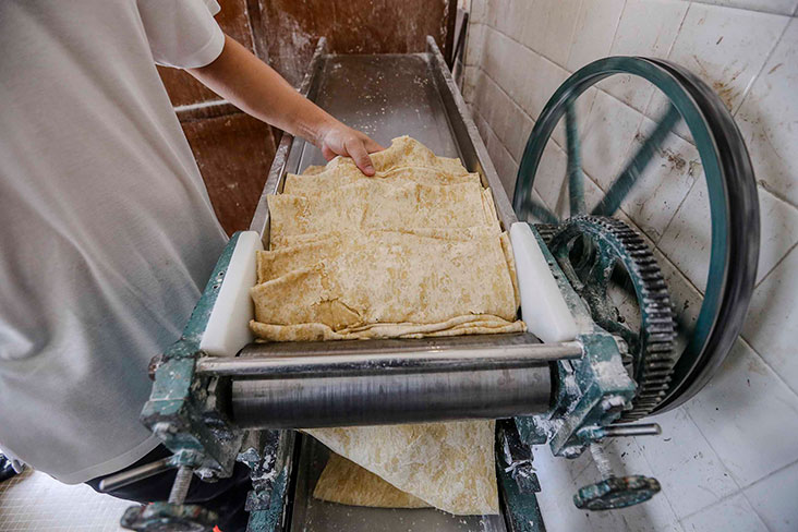 The flattened sheets of dough goes through many rounds before it is smooth and the right size for the noodles.