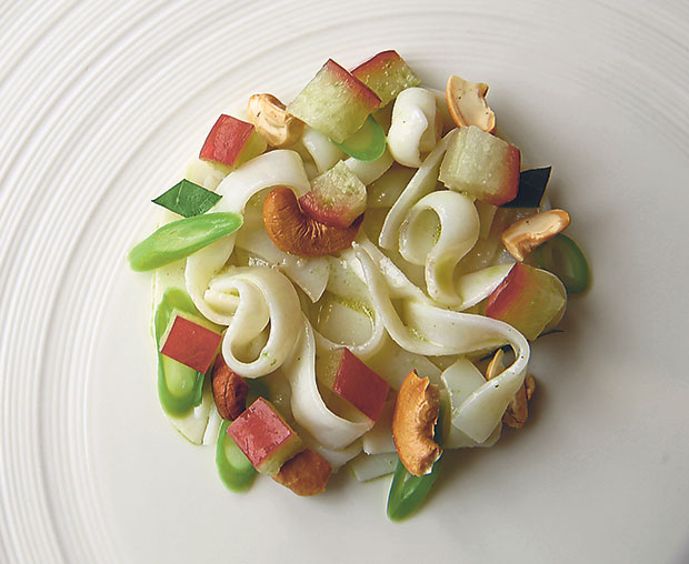 A view of the cuttlefish appetiser before the snow is added; you have sautéed strips of cuttlefish, toasted cashew nuts, long beans, diced jambu air (rose apple) and a herb known as tenggek burung