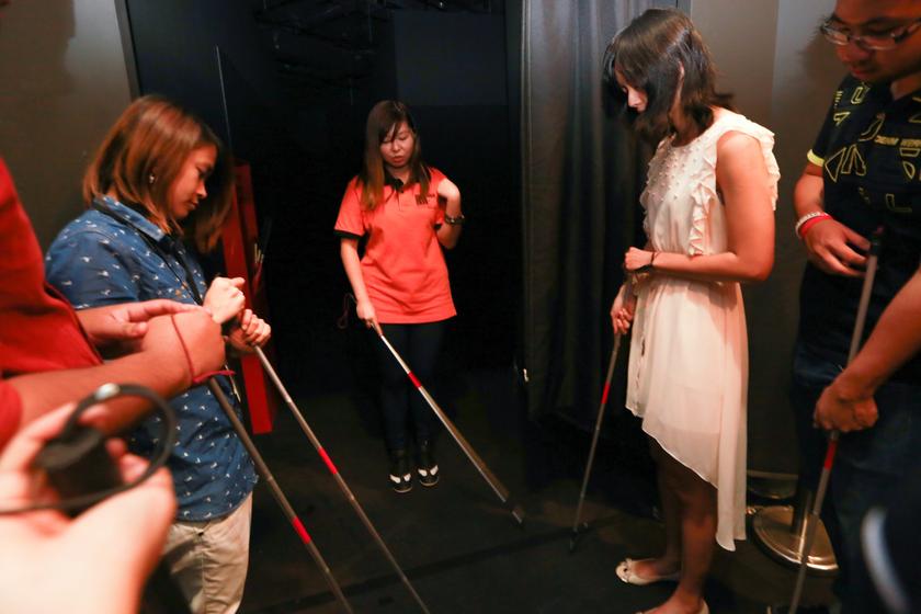 Visitors are given a briefing on how to use their cane to help them ‘see’ in the dark. — Picture by Saw Siow Feng