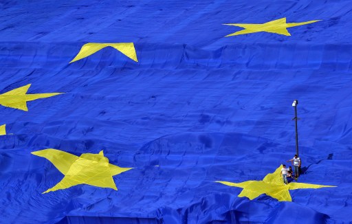 Workers walk over a giant flag of the European Union (EU) in front of the Parliament building in Bucharest May 9, 2013. u00e2u20acu201d AFP pic
