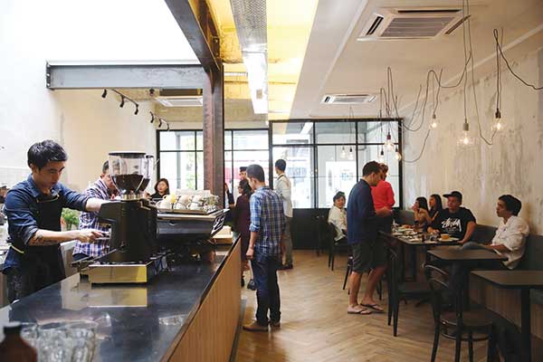 Enjoy your coffee in the clean space of bare stripped walls lit with hanging bulbs