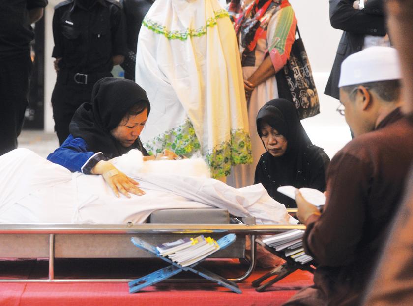 Hussain Ahmad Najadi's widow, Cheong Mei Kuen (left) paying her last respects at the Federal Territories Mosque in Jalan Duta last night. His body was later burried at  the Mont Kiara Muslim Cemetery. 