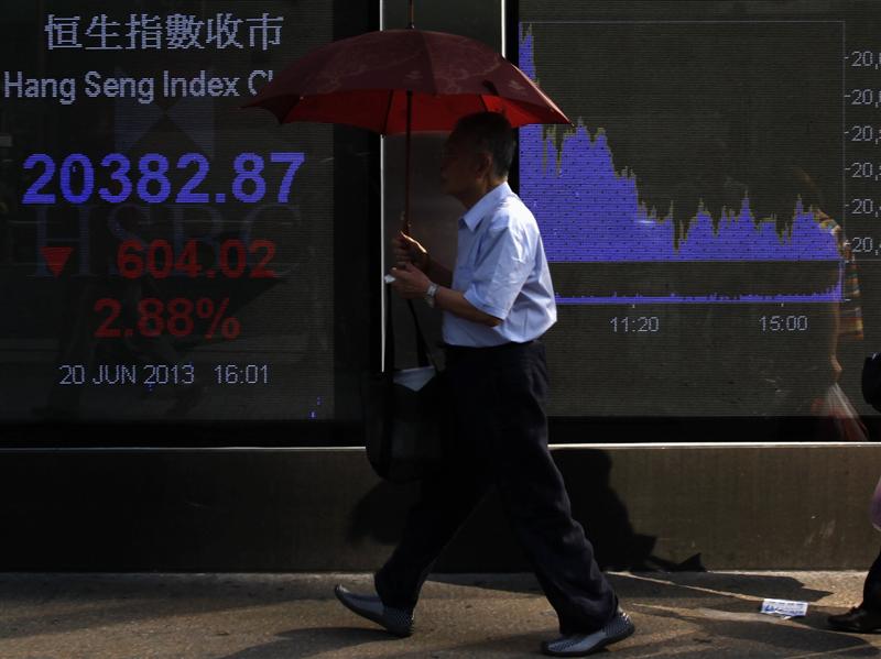 Undated file photo shows a man walking past a panel displaying the closing Hang Seng Index in Hong Kong. u00e2u20acu201d Reuters pic