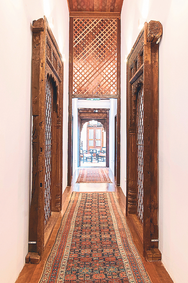 The corridor to the family suites with doors adorned by carved wooden arches and the wood lattice that is one of the mansion’s central theme.