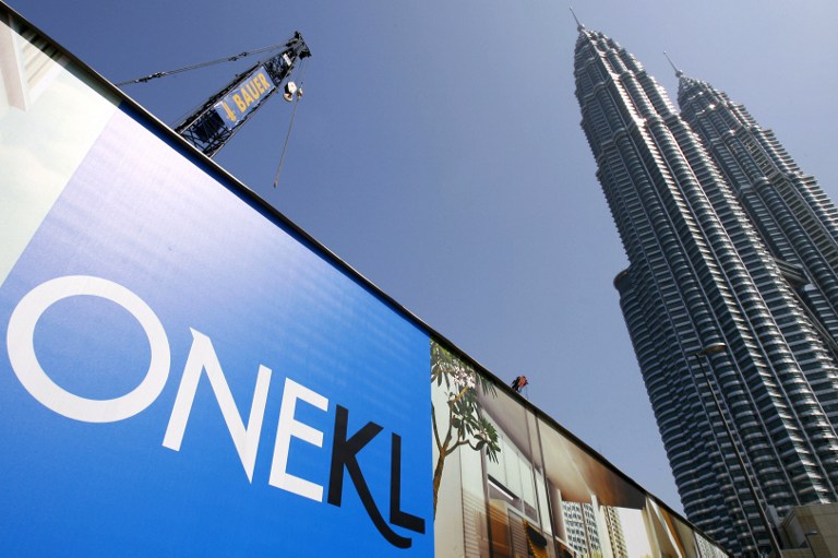 A construction crane stands behind a barrier covered with property advertising for the One KL luxury apartments, being built next to the landmark Petronas Twin Towers, in downtown Kuala Lumpur, 12 March 2006. u00e2u20acu201d AFP pic