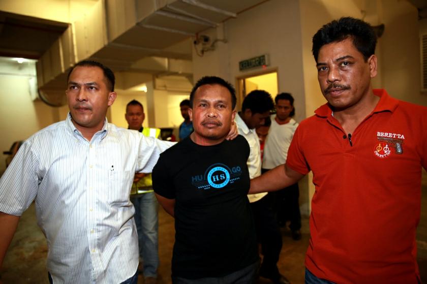 La Ode Ardi Rasila, the main suspect in the shooting of an Ambank officer, is being escorted by policemen in Kuala Lumpur, November 19, 2013. u00e2u20acu201d Picture by Saw Siow Feng